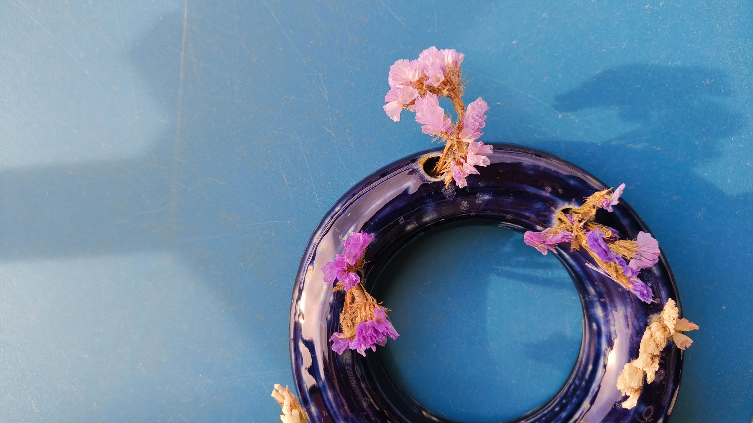 Jarrón de cerámica azul hecho a mano con flores secas rosas